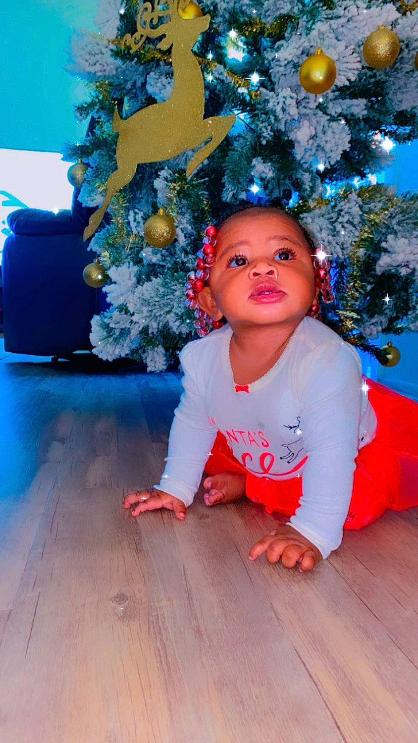 Kamiah is registered to the contest to win money with this photo: baby_toddler_clothing, blue, christmas, christmas_decoration, christmas_eve, christmas_ornament, christmas_tree, floor, flooring, holiday, holiday_ornament, human, interior_design, laminate_flooring, majorelle_blue, mouth, ornament, person, toddler, wood