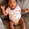 baby, infant, child, onesie, couch, sofa, earrings, curly_hair, cute, chubby, relaxed, indoor, portrait, comfort, skin, feet, arms, legs, looking, expression