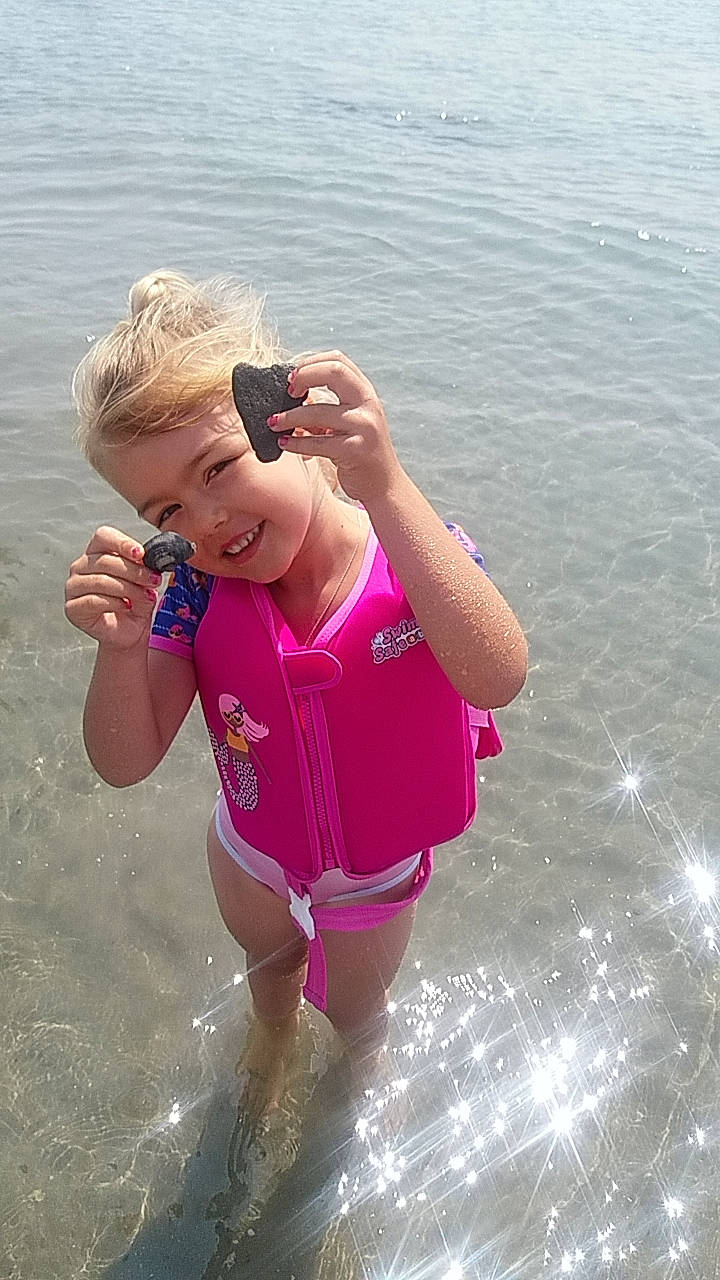 Jade a rejoint le concours — aidez-le/la à gagner de superbes lots ! arm, child, facial_expression, fun, hand, happy, joy, lake, leisure, one_piece_swimsuit, people_in_nature, person, personal_protective_equipment, play, recreation, shorts, smile, swimwear, thigh, toddler