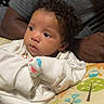 Emberlynn joined the competition — help win amazing prizes! baby, child, curly_hair, white_sweater, mittens, cushion, giraffe_pattern, tree_pattern, adult, gray_shirt, indoor, portrait, resting, colorful, cute, infant, person, closeup, young_child, face