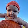 Evaleighn is registered to the contest to win money with this photo: baby, child, pumpkin, orange_beanie, outdoor, sky, autumn, cute, smile, face, headwear, nature, seasonal, person, young_child, daylight, cheeks, curious, portrait, holiday