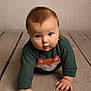 Arthur is registered to the contest to win money with this photo: baby, child, crawling, green_sweater, fox_design, floor, wooden_floor, curious, hands, portrait, cute, indoor, young_child, infant, face, eyes, warm_lighting, sweater, person, closeup