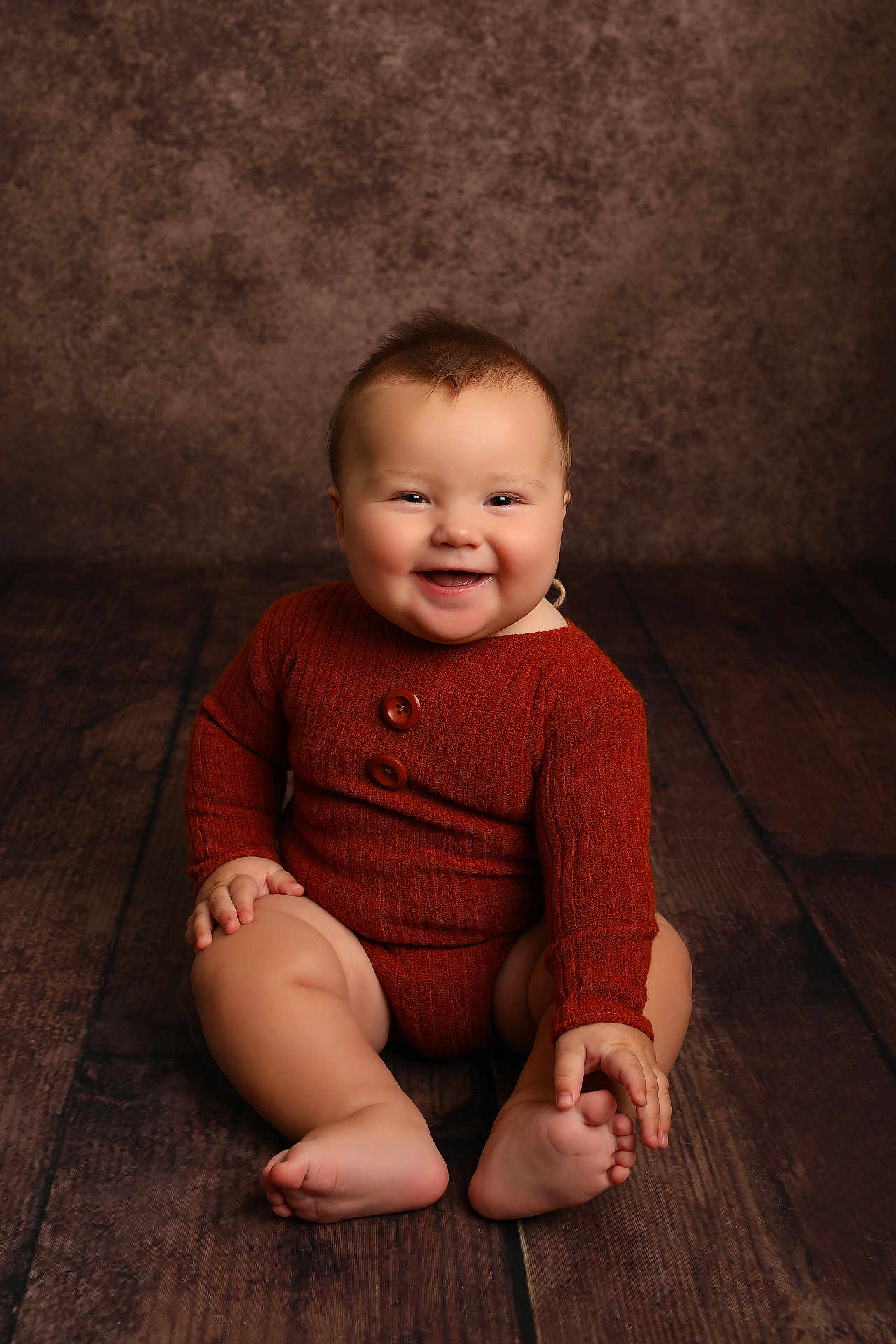 Arthur joined the competition — help win amazing prizes! baby, smiling, sitting, child, rustic_floor, knitwear, orange_outfit, cute, happy, portrait, infant, chubby, toothless_grin, wooden_floor, studio_lighting, indoor, cozy, buttoned_outfit, small_hands, barefoot