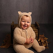 Arthur is registered to the contest to win money with this photo: baby, child, smiling, fuzzy_clothing, bear_ears, onesie, cute, sitting, wooden_box, smile, portrait, indoor, studio, infant, happy, plush, hands, face, cozy, toddler
