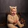 baby, child, smiling, fuzzy_clothing, bear_ears, onesie, cute, sitting, wooden_box, smile, portrait, indoor, studio, infant, happy, plush, hands, face, cozy, toddler