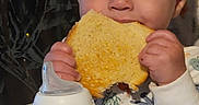 Noah joined the competition — help win amazing prizes! baby, child, infant, portrait, sitting, eating, bread, snack, sippy_cup, bottle, bib, high_chair, hands, face, eyes, smiling, indoor, home, patterned_clothing, breakfast