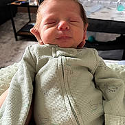 Luca is registered to the contest to win money with this photo: newborn, baby, infant, sleeping, onesie, clothing, face, head, hand, indoor, living_room, crib, furniture, soft_light, peaceful, child, person, portrait, cozy, resting