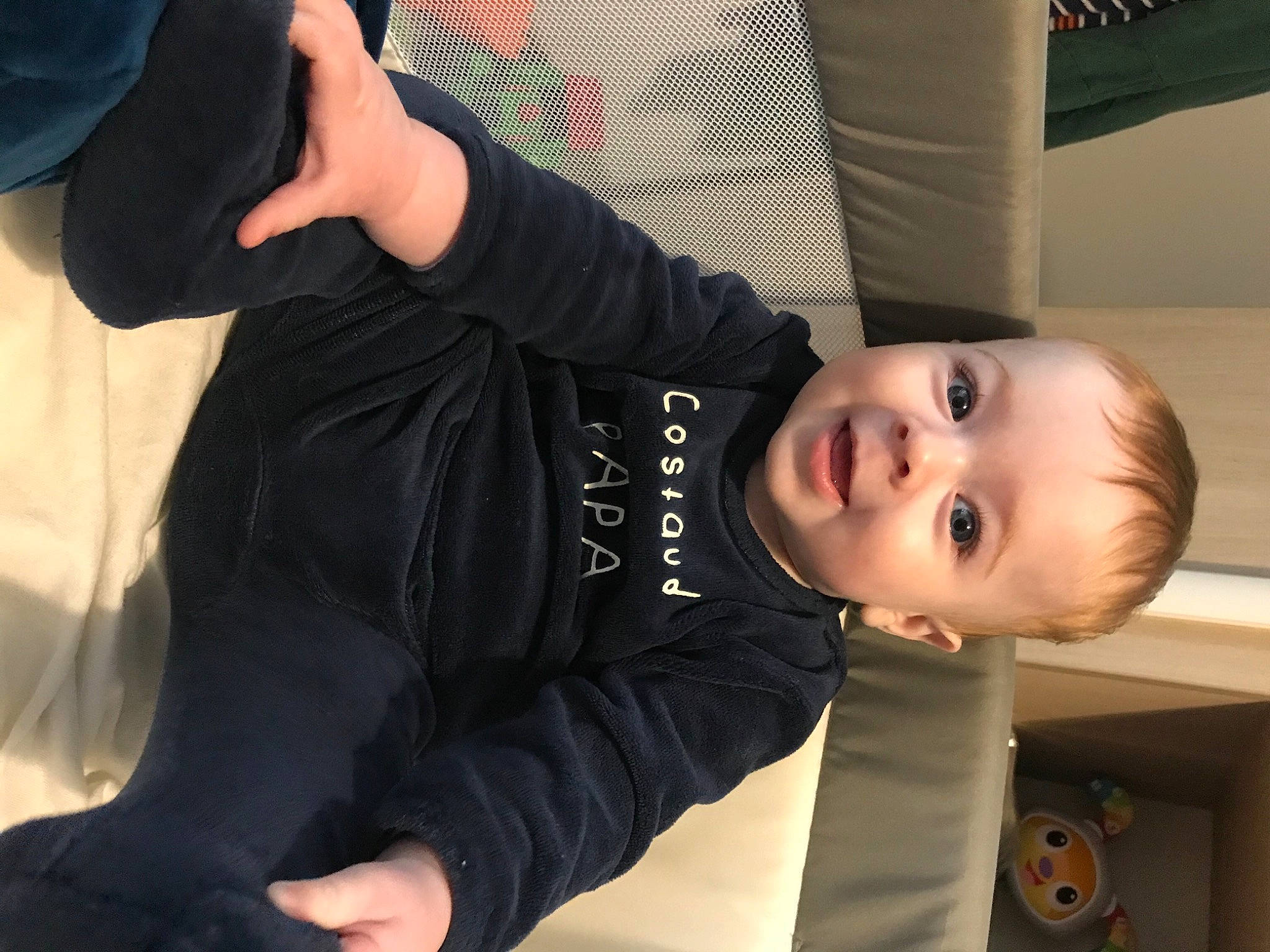 Lény participe au concours pour gagner de l'argent avec cette photo : arm, baby, baby_toddler_clothing, cheek, child, comfort, elbow, fun, gesture, hand, joint, knee, mouth, person, sitting, sleeve, smile, thumb, toddler, wood