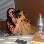Marley a rejoint le concours — aidez-le/la à gagner de superbes lots ! woman, dog, hug, indoor, table, phone, bottle, box, window_shutter, brown_wall, flash, affection, pet, casual, long_hair, bracelet, tattoo, plastic_chair, collar, hand