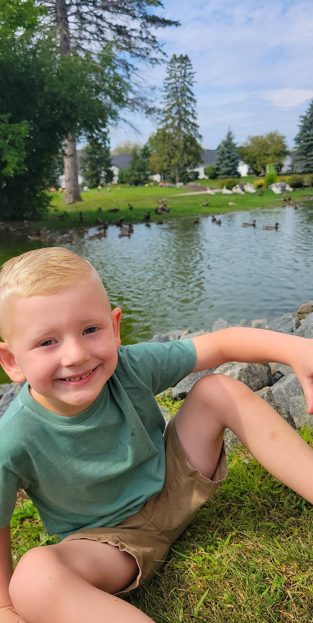 Easton is registered to the contest to win money with this photo: bank, body_of_water, botany, cloud, cool, grass, happy, human_body, joy, lake, leaf, leisure, nature, people_in_nature, person, plant, sky, smile, summer, tree