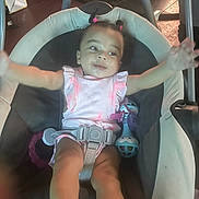 Zaierra joined the competition — help win amazing prizes! baby, infant, child, baby_seat, toy, pink_clothing, hair_ties, indoor, floor, happy, arms_outstretched, seat_belt, face, legs, foot, playtime, childcare, cushion, person, cute