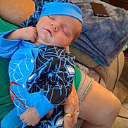 Alekhi James is registered to the contest to win money with this photo: baby, blanket, blue_clothing, casual, comfort, couch, cozy, hand, home, indoor, infant, legs, person, phone, relaxing, rest, ring, sleeping, soft, spider_web_pattern