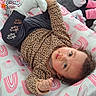 Jenaiah participe au concours pour gagner de l'argent avec cette photo : baby, blanket, child, couch, curly_hair, floor_tile, indoor, infant, leopard_print, looking_up, onesie, patterned_clothing, pillow, playful, plush_toy, portrait, resting, slipper, sock, sofa