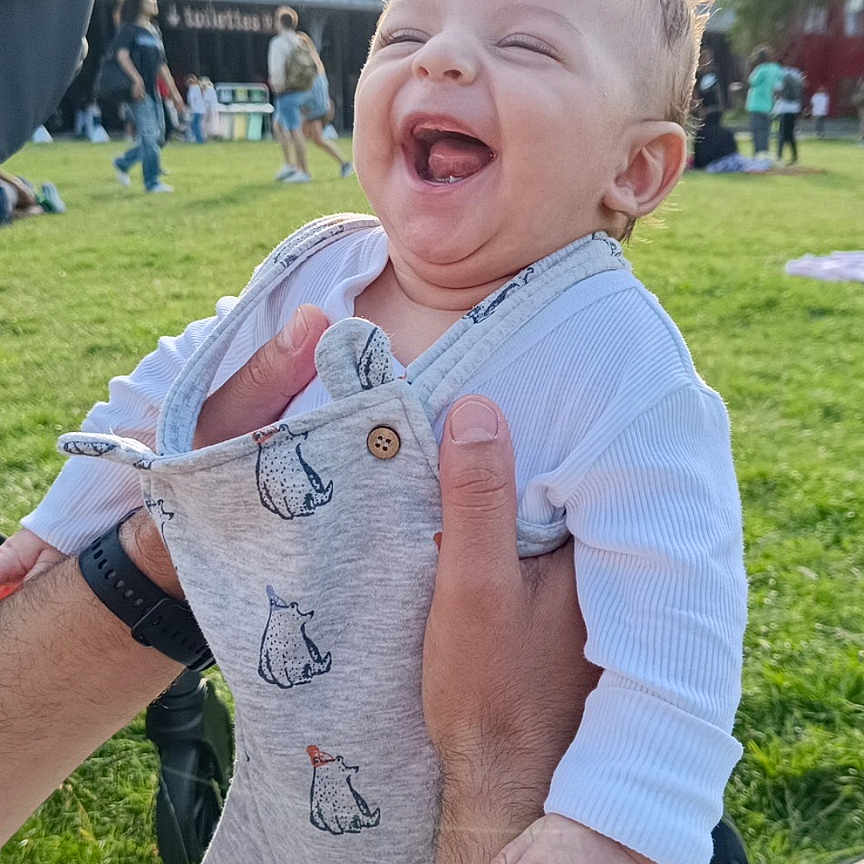 Daris participe au concours pour gagner de l'argent avec cette photo : adult, baby, casual, child, clothing, cute, daylight, fun, grass, hands, happy, human, infant, joy, laughing, outdoor, overalls, park, people, smiling