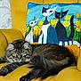 cat, tabby_cat, fluffy, yellow_chair, pillow, cartoon_cats, floral_pattern, indoor, pet, animal, relaxed, feline, fur, face, whiskers, ears, couch, colorful, decor, resting