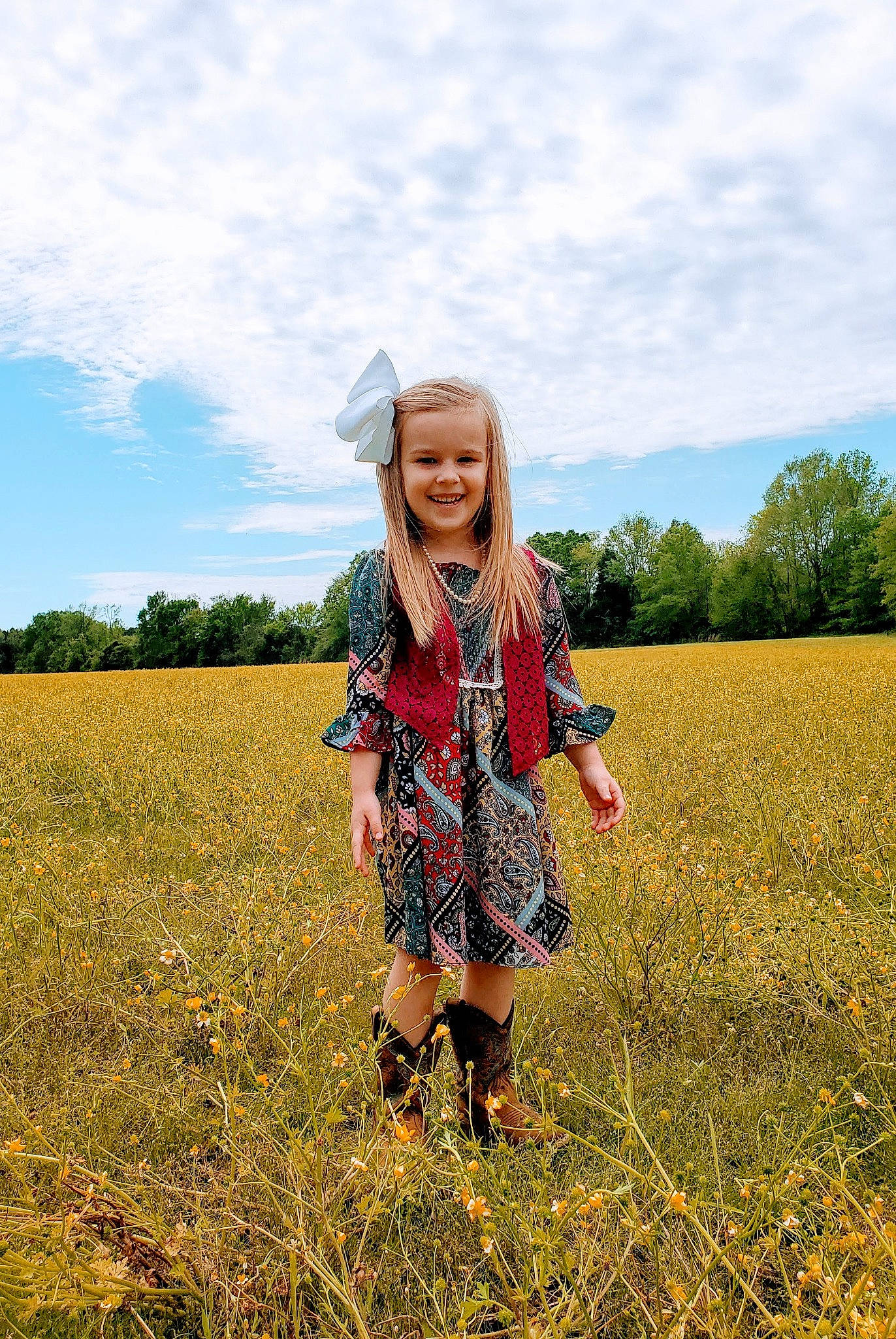 Brylee is registered to the contest to win money with this photo: agriculture, clothing, cloud, flower, grass, grassland, happy, hat, headgear, joy, landscape, mammal, meadow, people_in_nature, person, plain, plant, sky, smile, summer