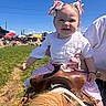 baby, child, horse, saddle, outdoor, sunny, grass, blue_sky, person, smiling, pink_bows, white_clothing, holding_hands, watch, event, umbrella, fair, happy, portrait, cute