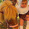 baby, pony, animal, child, outdoor, grass, vintage_clothing, bonnet, lace, cute, pet, farm, saddle, sky, fence, person, footwear, rural, summer, nature