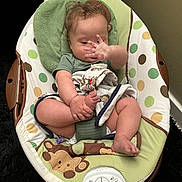 Karsten is registered to the contest to win money with this photo: baby, infant, child, sitting, bouncer, baby_chair, blanket, green, polka_dots, monkey_pattern, hand, face, brown_hair, indoor, home, cozy, portrait, relaxed, playful, photography