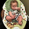baby, infant, child, sitting, bouncer, baby_chair, blanket, green, polka_dots, monkey_pattern, hand, face, brown_hair, indoor, home, cozy, portrait, relaxed, playful, photography