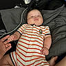 Karsten is registered to the contest to win money with this photo: baby, infant, child, onesie, striped_clothing, monkey_patch, hand_holding, blanket, bottle, bedroom, couch, person, skin, fingers, foot, fabric, casual, relaxing, indoor, cute
