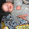 baby, sleeping, onesie, striped_clothing, hand, blanket, bear_pattern, toy, colorful, infant, child, peaceful, resting, indoor, cozy, soft_texture, person, cute, sleep, closeup
