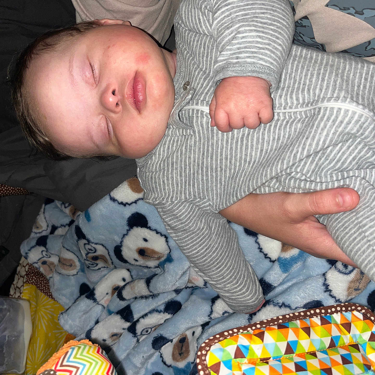 Karsten joined the competition — help win amazing prizes! baby, sleeping, onesie, striped_clothing, hand, blanket, bear_pattern, toy, colorful, infant, child, peaceful, resting, indoor, cozy, soft_texture, person, cute, sleep, closeup