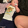 Karsten is registered to the contest to win money with this photo: baby, infant, pacifier, tiger, shirt, clothing, blanket, sock, leg, person, child, bedroom, fabric, lying_down, cute, indoor, skin, footwear, resting, soft