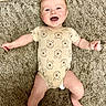 Oliver is registered to the contest to win money with this photo: baby, infant, smiling, onesie, bear_pattern, carpet, floor, happy, child, cute, lying_down, playful, skin, head, arms, legs, indoors, texture, toddler, expression