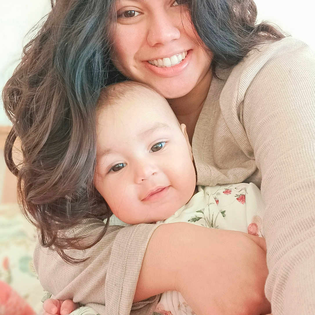 Komal joined the competition — help win amazing prizes! baby, child, clothing, comfort, cozy, cuddle, expression, face, family, floral_pattern, hug, indoor, long_hair, love, person, portrait, smile, soft_light, warmth, woman