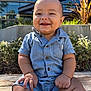 baby, child, smiling, denim, romper, outdoor, sunlight, wooden_surface, building, greenery, happy, portrait, sitting, cute, infant, casual_clothing, daylight, nature, human, baby_boy