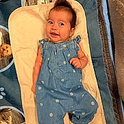 Ryan is registered to the contest to win money with this photo: baby, infant, smile, blue_romper, hair_tuft, blanket, dog_pattern, cute, child, lying_down, happy, playful, indoors, soft_texture, young_child, apparel, small_person, portrait, cozy, comfort