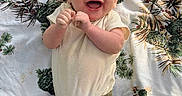 Tanner is registered to the contest to win money with this photo: baby, blanket, child, clothing, cream_shirt, eyes, face, green_pants, hands, happy, indoors, infant, lying_down, mouth, patterned_blanket, photography, pinecones, plants, portrait, smiling