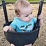 toddler, baby, swing, playground, outdoor, child, blue_shirt, wood_chips, fence, plastic, grass, summer, daylight, curious, seat, holding, nature, cute, young_child, park
