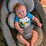 baby, infant, baby_rocker, snoopy, tshirt, blue_clothing, indoor, carpet, wood_paneling, baby_seat, child, person, face, legs, feet, expression, furniture, floor, home, cute