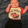baby, infant, child, blanket, clothing, hot_wheels, shirt, pants, black_pants, lying_down, indoor, cute, young, portrait, person, face, wide_eyes, soft_texture, red_shirt, baby_clothes