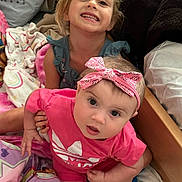 Indie Ana joined the competition — help win amazing prizes! child, baby, smiling, headband, pink_clothing, blanket, bed, pillow, indoor, cute, happy, sitting, two_children, portrait, face, young, curious, cozy, toddler, playful