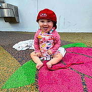 Indie Ana is registered to the contest to win money with this photo: barefoot, casual, child, colorful_clothing, floor_pattern, flower_shape, fun, hat, outdoor, person, philadelphia_phillies, playful, playground, red_cap, sitting, smiling, toddler, tongue_out, towel, young_child
