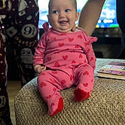 Harper joined the competition — help win amazing prizes! adult_hands, baby, book, cozy, face, happy, heart_pattern, home, indoor, infant, number_9_3_4, onesie, ottoman, owl_pattern, pajamas, person, pink_clothing, sitting, smiling, soft_lighting