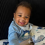 Ronald joined the competition — help win amazing prizes! baby, smiling, child, blue_shirt, cushion, dinosaur_pattern, pacifier, indoor, happy, face, clothing, seated, toddler, cozy, home, portrait, hand, comfort, cute, infant