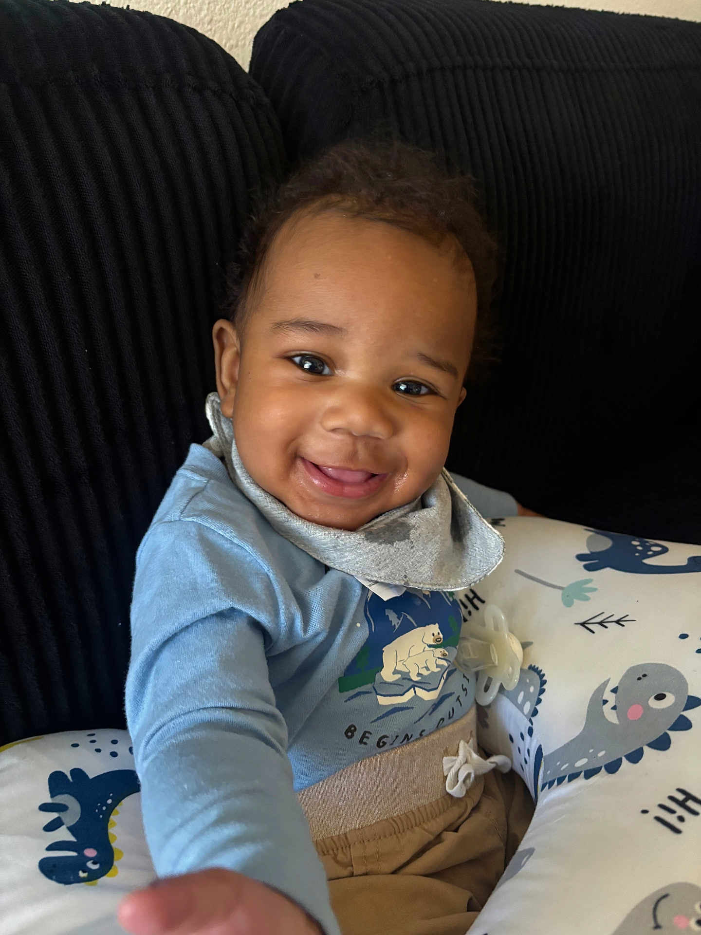 Ronald joined the competition — help win amazing prizes! baby, smiling, child, blue_shirt, cushion, dinosaur_pattern, pacifier, indoor, happy, face, clothing, seated, toddler, cozy, home, portrait, hand, comfort, cute, infant