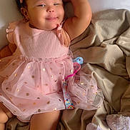 Truth is registered to the contest to win money with this photo: baby, bed, blanket, child, cozy, cute, girl, happy, headband, indoor, infant, pink_dress, polka_dots, portrait, relaxed, resting, smiling, socks, soft_lighting, tulle