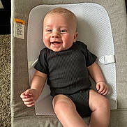 Jaxx joined the competition — help win amazing prizes! baby, infant, smiling, onesie, baby_seat, cushion, carpet, indoor, child, happy, skin, face, arm, leg, footwear, white_sock, closeup, portrait, comfort, relaxing