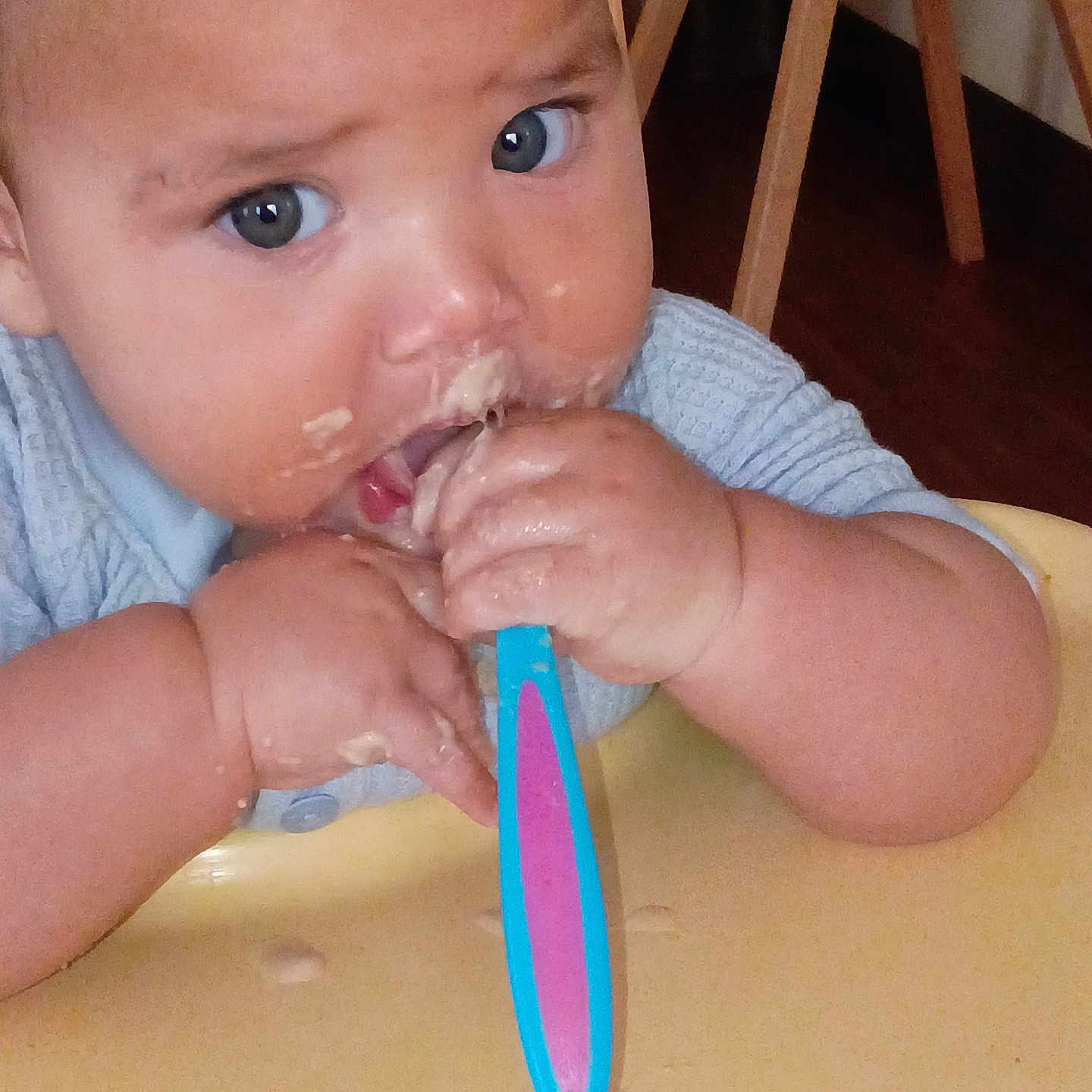 Jamahl joined the competition — help win amazing prizes! baby, child, spoon, food, messy, high_chair, hands, face, blue_eyes, clothing, wooden_chair, table, feeding, eating, cute, indoor, infant, person, closeup, expression