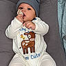 baby, beanie, child, cute, deer, gray, headwear, infant, lying_down, onesie, pacifier, person, plush, resting, soft, teether, white_clothing, young_child, indoor, comfort