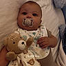 Ace joined the competition — help win amazing prizes! baby, pacifier, teddy_bear, blanket, bed, infant, clothing, bib, hand, face, person, cute, lying_down, soft_toy, sleepwear, child, indoors, comfort, young, cozy