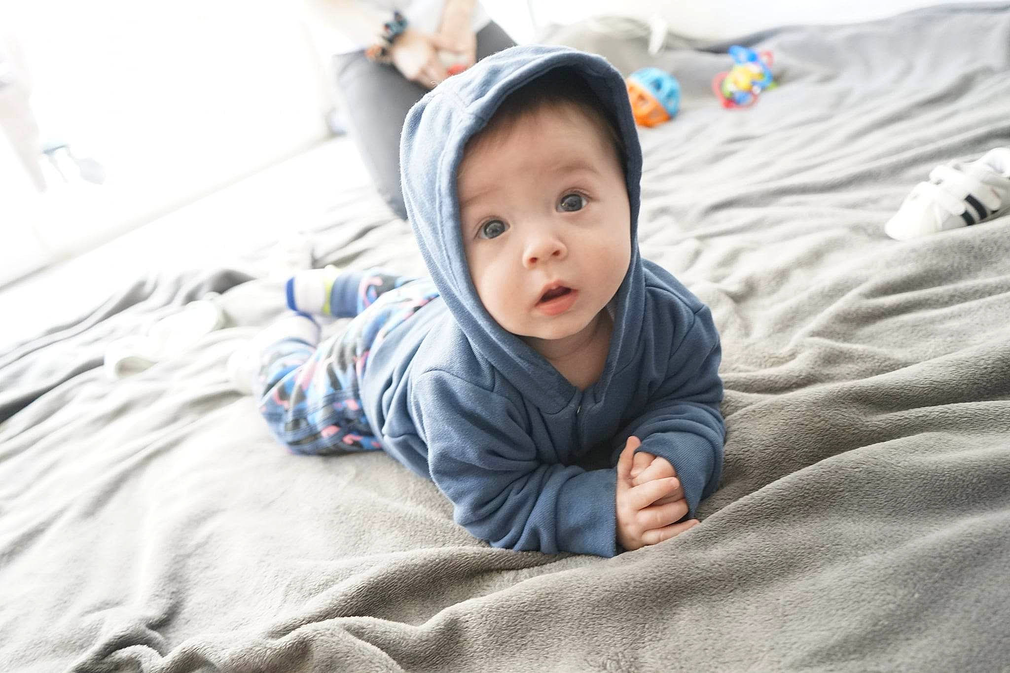 Logan a rejoint le concours — aidez-le/la à gagner de superbes lots ! baby, baby_toddler_clothing, child, comfort, flash_photography, flooring, fun, grass, grey, happy, linens, person, portrait_photography, room, sitting, skin, sleeve, smile, surprise, t_shirt