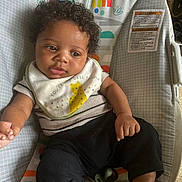 Yazariahla joined the competition — help win amazing prizes! baby, infant, curly_hair, bib, pacifier, baby_seat, animal_print, clothing, black_pants, cute, child, indoor, relaxed, looking_away, colorful, playful, comfort, seat, young, adorable