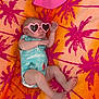 baby, infant, sunglasses, heart_shaped, towel, palm_tree_pattern, pink_hat, onesie, relaxing, summer, outdoor, colorful, cute, lying_down, barefoot, fashion, accessory, skin, head, hand