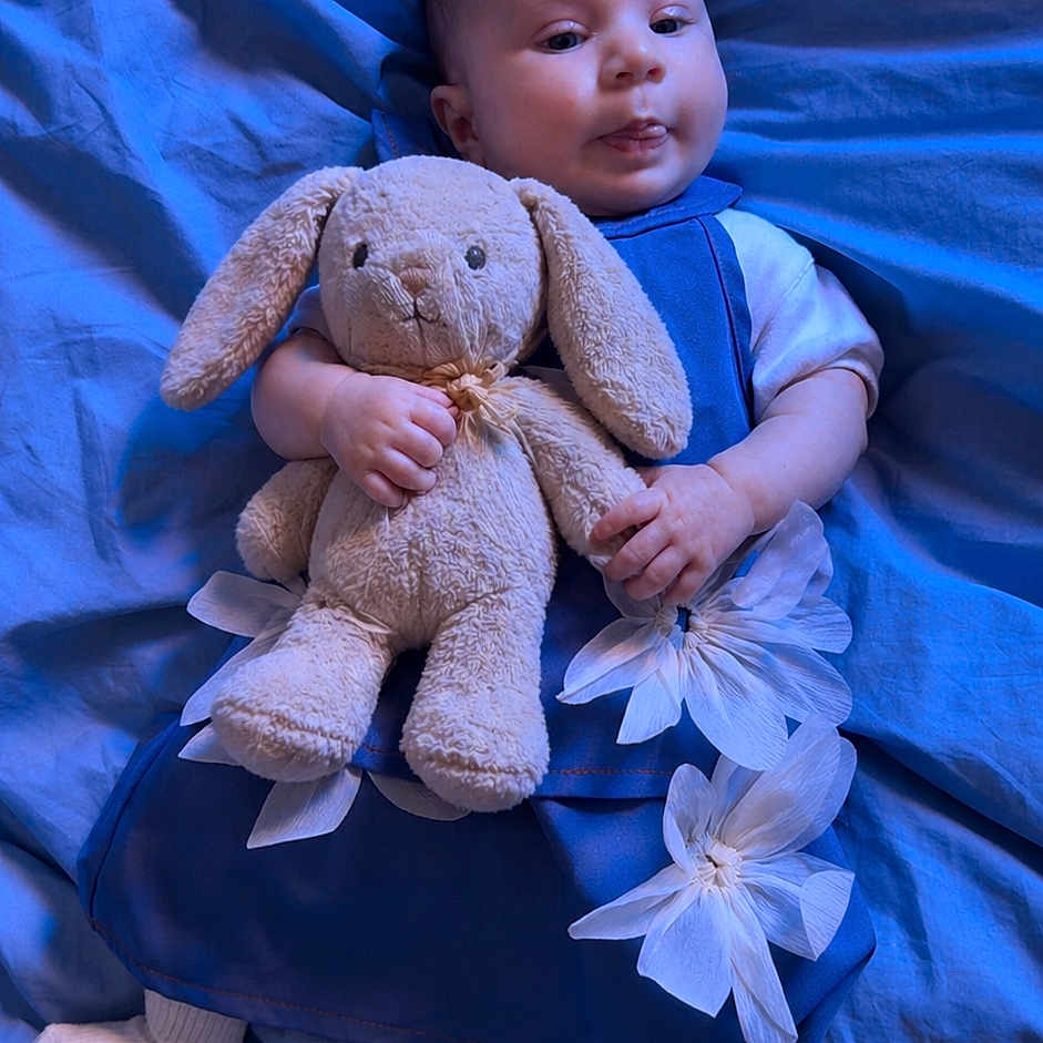 Lévanna participe au concours pour gagner de l'argent avec cette photo : baby, plush_bunny, blue_blanket, blue_outfit, white_flowers, socks, infant, child, cute, soft_toy, lying_down, indoors, portrait, small_hands, head, face, expression, cozy, comfort, toddler